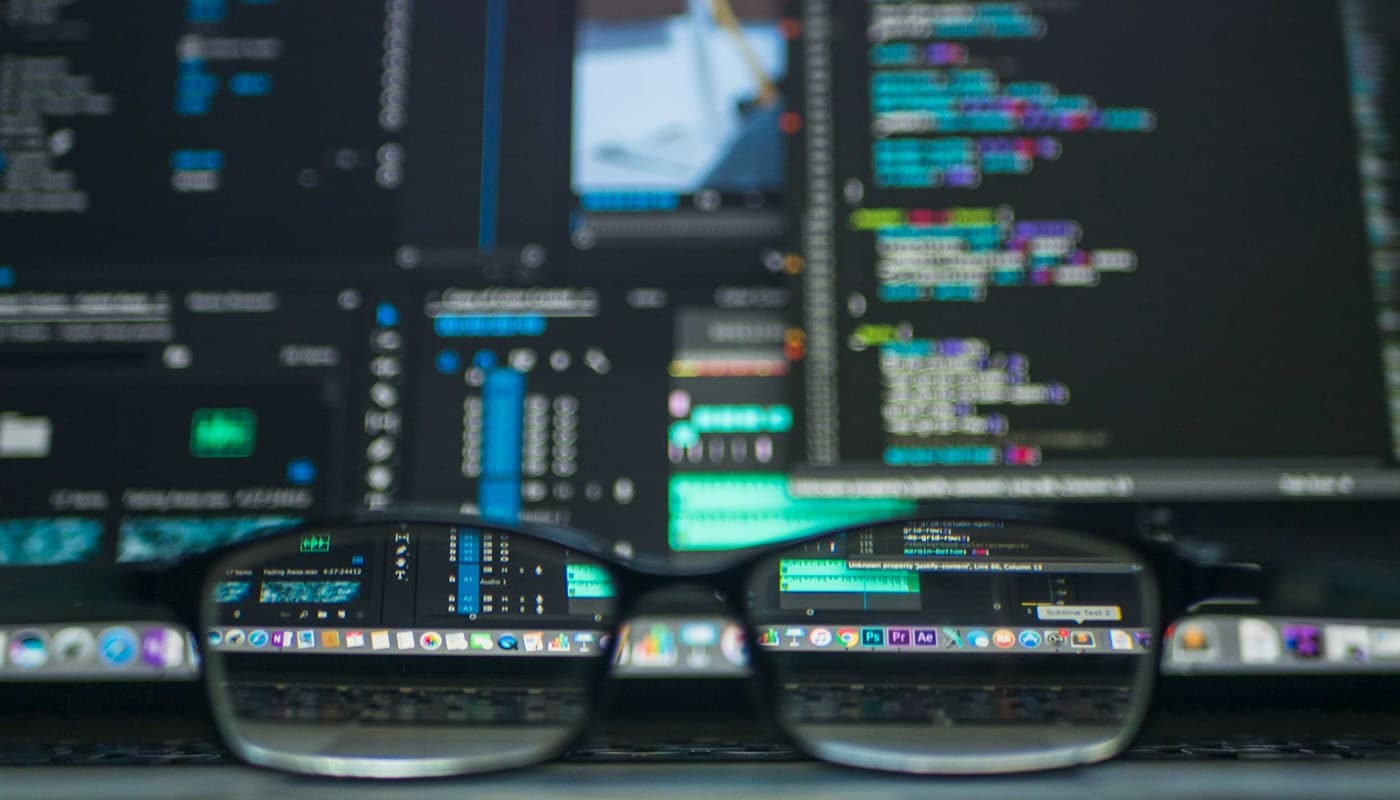 Eyeglasses in front of computer screens displaying source code